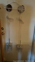 Two chrome pendant lights hanging on wall hooks showing cords and chrome bases