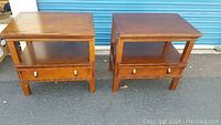 Two wooden nightstands side by side, each with a drawer and shelf, minor scratches visible on top surfaces