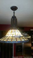 Full view of Tiffany style pendant chandelier hanging from ceiling showing stained glass shade and metal chain fixture.