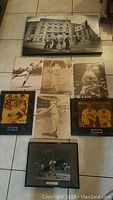 Overview of all eight baseball pictures laid out on floor including various framed photographs and one large stadium wall picture