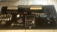 Overview of lot on black surface showing flatware, scrap pile, coin and jewelry