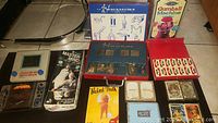 Overview of multiple games and items including Magnatiks box, playing cards, Master Mind board game box, Naked Truth card game, and bank gumball machine.