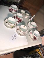 All items consisting of 6 teacups and saucers, one creamer, one sugar bowl, and one small vase arranged on a table with floral patterns and gold trim