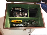 Open case showing Kodak Kalart camera, Kodak Professional film box, lens attachment, and flash bulbs inside a green felt-lined carrying case.