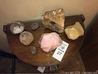 Seven assorted rocks and geodes displayed on a wooden table from a frontal angle showing colors, sizes and textures.
