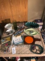 Full assortment spread showing Pyrex nested bowls, green glass tumblers, decorative trays, metal utensils, and various vintage kitchenware items.
