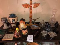 Photo showing southwestern and Inuit style decorative items on black table, including totem pole, pottery, glassware and sculptures