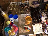 Overview photo showing brass candlesticks at the rear, plastic mugs, utensil holder with utensils, glassware, planter, and napkin holder on table