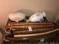 Overview of wooden walking sticks, vintage ruler, and Syroco wall decor pieces placed on furniture.