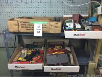 Overview of various train cars, tools, and model building parts in open boxes showing assorted contents.