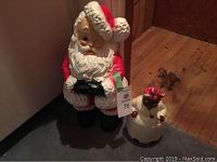 Retro style plastic Santa Claus and vintage ceramic cookie jar with matching thimble, displayed together on floor near wall.