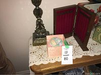 Photo of the lamp, necklace holder closed and powder box on a wooden surface with lace cover