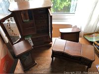 Four wooden jewelry boxes displayed on table near window, including a tall box with glass doors and multiple smaller boxes.