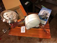 Ceiling light fixture, shoe polisher in box, and small portable fan arranged on table