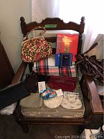 Vintage purses and blankets arranged on a wooden chair with three photo albums on top of a plaid blanket.