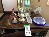 View of assorted decorative items including the glass cabinet, perfume bottle, candle holders, figurines, and decorative plate stand.