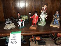 Shelf with metal miniature models of horse-drawn wagons, Yeoman Warder figure, and ceramic figures