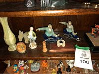 Porcelain Asian and animal figurines on wooden shelf with decorative vase and candlestick
