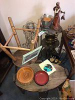 Overview of stand with figurine on top, wooden stools, bowls and decorative items spread out on surfaces