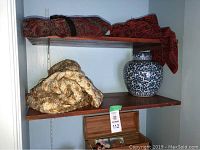 Display shelf with three white and gold garments and a blue and white porcelain vase