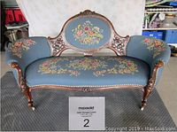Full front view of settee showing overall shape, upholstery, and carved wood frame