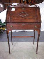 Full front view of the oak ladies writing desk showing carved details and brass hardware.