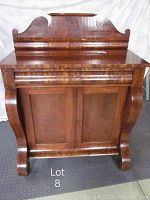 Front view of antique wood veneered sideboard showing decorative curved legs and sculpted backboard area.