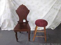 Wide view showing antique solid wood chair with decorative back and oak stool with padded seat side by side.