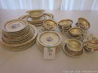Photo showing the stacked plates, multiple cups and saucers, and serving pieces arranged together showing the full content of the lot.