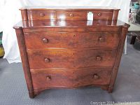 Front view of antique wooden dresser showing three large drawers and three small top drawers with round wooden knobs, wood veneer finish, and keyholes visible.
