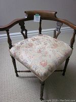 Front view showing floral upholstered seat, carved wooden frame with rounded top back rail and turned legs.