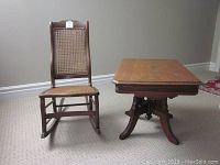Antique nursing rocking chair next to solid oak coffee table on carpeted floor.