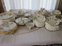 Full display of hand painted china set on a table, showing plates, serving dishes, cups, and saucers