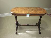 Front view of antique game table showing wood grain inlay top and carved front legs.