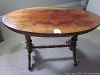 Full view of the sturdy oval table showing wood veneer top with grain and turned legs