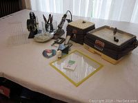 Wide view of table showing machines, tools, foil dispenser and rack