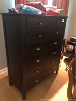 Full view of a dark wooden dresser with six drawers and items on top (items not included).
