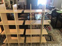 Photo showing the wooden book shelf with staggered shelves and the metal adjustable floor lamp standing against it in a living room environment.