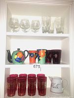 Second shelf showing J Mrazek hand-painted teapot and matching floral cups, and cranberry colored glasses