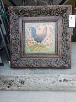 Full view of the framed rooster art piece showing ornate carved wooden frame with floral motifs.