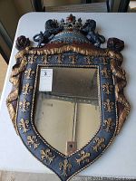 Front view of Renaissance style mirror with fleur-de-lis design and lion crown top.