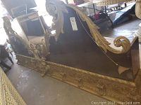 Full side-angle view of the large ornate gold frame mirrored headboard, showing carved scrolls and floral details, with the mirror panel intact but showing damage on one side.