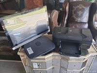 Overview of the monitor, cooling fan, printer and keyboard on a table.