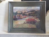 Framed landscape artwork by Kim Wallis in dark wooden frame with visible wear and scratches.