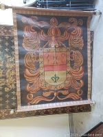 Full view of the painted fabric tapestry showing the coat of arms design and ornamental border.