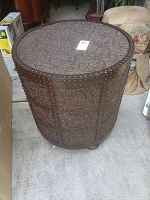 Overall view of round decorative metal side table with embossed floral panels and stud accents.