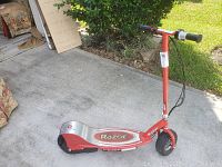 Red Razor E300 electric scooter on concrete with visible Razor logos on deck and frame, showing overall condition and design.