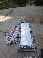 Two kids play teepees and standing zebra print mirror laid on driveway