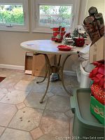 Full view of round stone top table with metal legs surrounded by household items.
