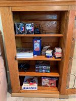 Wooden shelf with puzzles, playing card decks, domino games, dice, and Sequence board game box